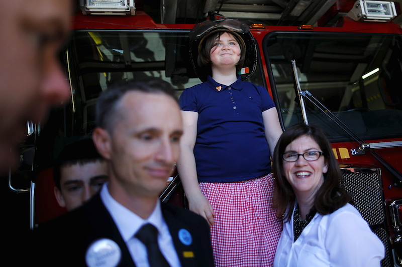 Jane Richard, the sister of Boston Marathon bombing victim Martin Richard, tries on a firefighters's helmet during a visit to the fire station on Boylston Street on the second anniversary of the Boston Marathon bombings in Boston. With her are her father Bill (left) and mother Denise (right).  Photo by REUTERS/Brian Snyder