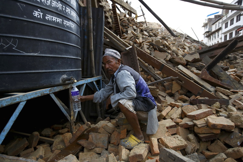 A man fills water from a water tank near a collapsed temple in Kathmandu, Nepal, a day after a 7.9 magnitude earthquake killed more than 2,400 people and devastated Kathmandu valley. Photo courtesy of REUTERS/Navesh Chitrakar