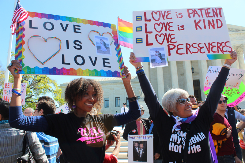Ikeita Cantu, left, and Carmen Guzman, of McLean, Va., hold signs in front of the Supreme Court on April 28, 2015 as justices inside considered arguments about legalizing same-sex marriage nationwide. They were married in 2009 in Canada. Religion News Service photo by Adelle M. Banks