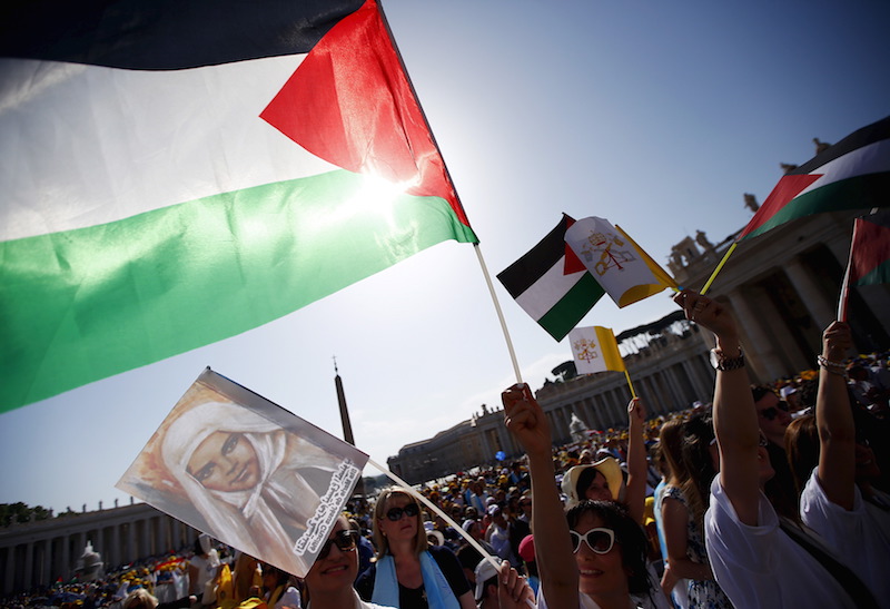 Members of the faithful wave Palestinian flags. The Vatican is unclear whether it will fly its own flag beside the Palestinian one at the United Nations.  Photo courtesy of REUTERS/Tony Gentile