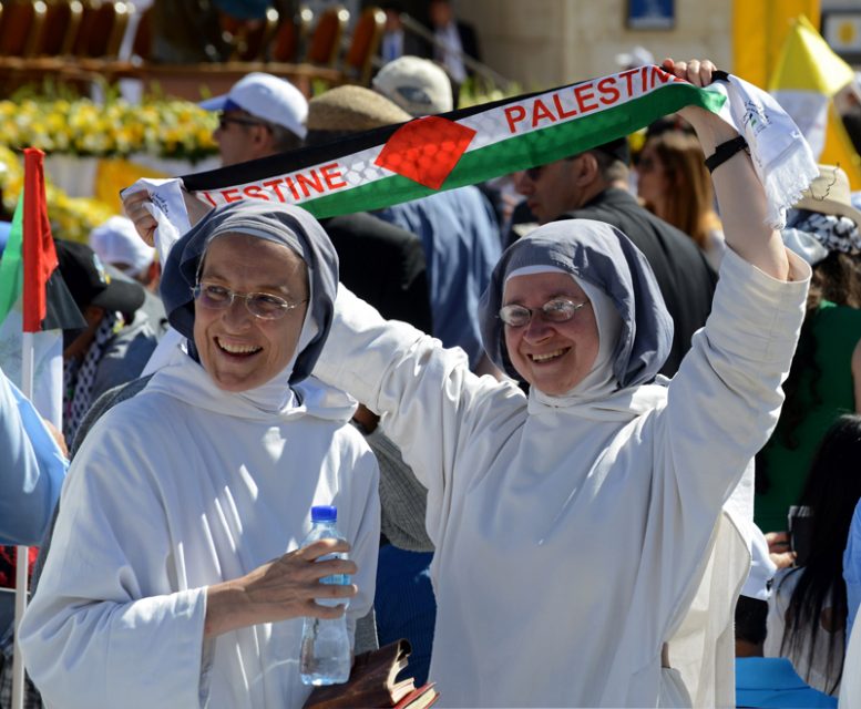 A nun holds up a scarf that reads 