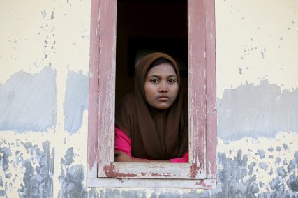 A Rohingya migrant woman, who arrived in Indonesia by boat, looks from a window of a shelter inside a temporary compound for refugees in Kuala Cangkoi village in Lhoksukon, Indonesia's Aceh Province, on May 17, 2015. The United Nations has called on countries around the Andaman Sea not to push back the thousands of desperate Bangladeshis and Rohingya Muslims from Myanmar now stranded in rickety boats, and to rescue them instead. Photo courtesy of  REUTERS/Beawiharta *Editors: This photo may only be republished with RNS-ROHINGYA-SPLAINER, originally transmitted on May 19, 2015.