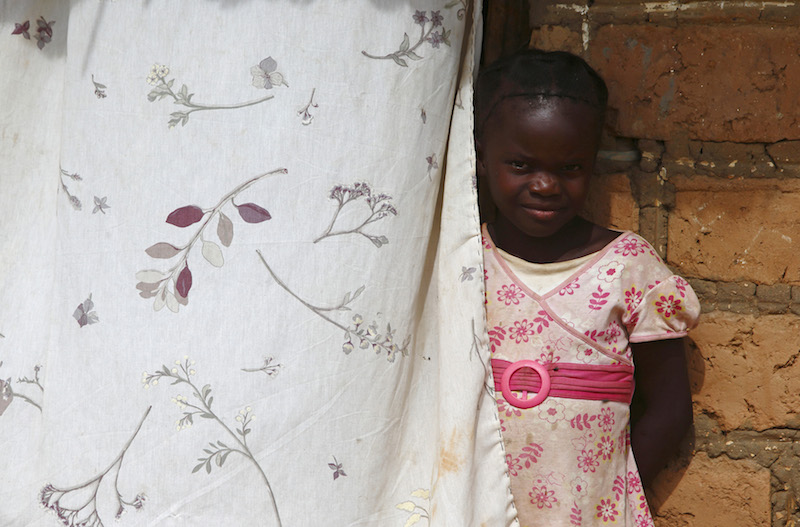 A child looks out from behind a curtain during a visit by a home-based care team to an HIV-positive person in the village of Choongo, south of the Chikuni Mission in the south of Zambia February 23, 2015. Photo courtesy of REUTERS/Darrin Zammit Lupi