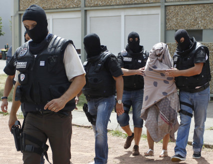 French police forces escort a woman from a residential building during a raid in Saint-Priest, near Lyon, France, June 26, 2015.