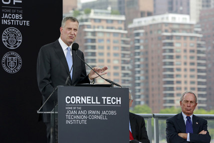 New York City Mayor Bill de Blasio speaks while former New York City mayor Michael Bloomberg looks on during a groundbreaking ceremony of Cornell Tech's campus on Roosevelt Island in New York on June 16, 2015. Photo courtesy of REUTERS/Shannon Stapleton