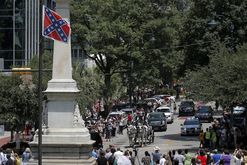 A horse drawn carriage carries the casket of the late South Carolina State Senator Clementa Pinckney past the Confederate flag and onto the grounds of the South Carolina State Capitol in Columbia, South Carolina June 24, 2015.  Photo by Brian Snyder courtesy of Reuters  
