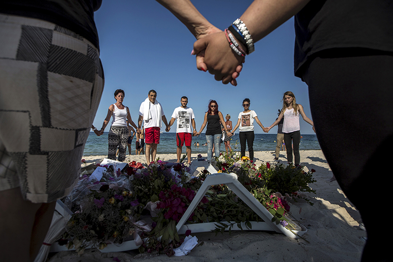 People hold hands as they pray in a circle around bouquets of flowers laid as mementos on the beach of the Imperial Marhaba resort, which was attacked by a gunman, in Sousse, Tunisia, on June 28, 2015. Photo courtesy of REUTERS/Zohra Bensemra
*Editors: This photo may only be republished with RNS-UK-EXTREMISTS, originally transmitted on June 30, 2015.