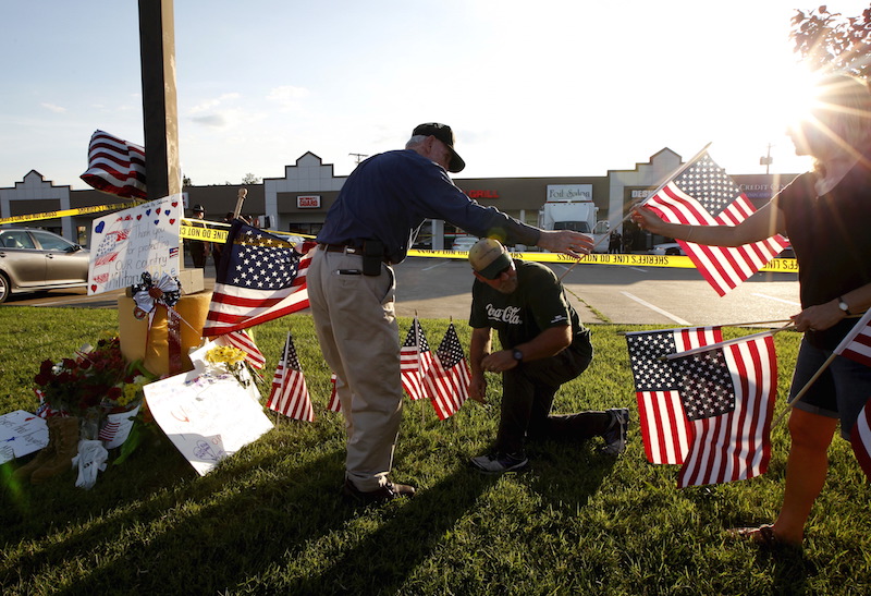 Mourners places flags at a growing memorial in front of the Armed Forces Career Center in Chattanooga, Tenn., on July 16, 2015. Four Marines were killed by a gunman who opened fire at two military offices in Chattanooga, before being fatally shot in an attack officials called a brazen, brutal act of domestic terrorism. Photo courtesy of REUTERS/Tami Chappell 