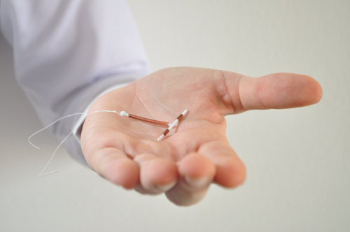 Holding an IUD birth control copper coil device in hand, used for contraception.