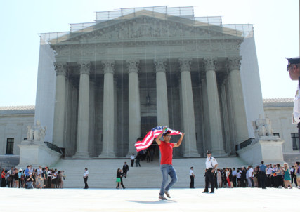 (RNS10-jun26) A man exits the Supreme Court building carrying an American flag after the high court made its rulings on same-sex marriage Wednesday (June 26). For use with RNS-PROP8-DECISION, transmitted on June 26, 2013, RNS photo by Adelle M. Banks.