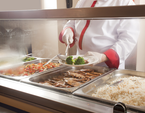 A chef serves lunch in a cafeteria.