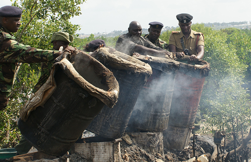 In an operationg against illicit brews in Mombasa, administration police officers prepare to pour out the brew from drums in 2013. Religion News Service photo by Fredrick Nzwili