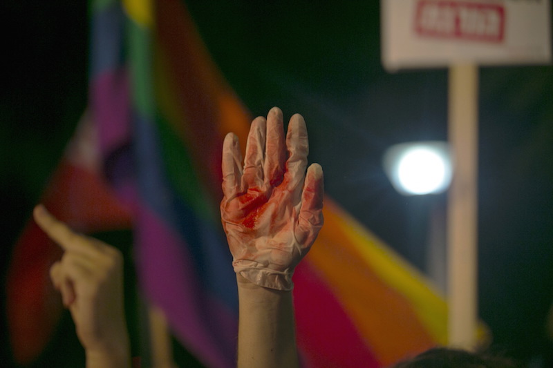 A protester holds up a glove covered in red during a protest against the violence towards the gay community in Tel Aviv August 1, 2015. Thousands of Israelis came to show solidarity after an ultra-Orthodox Jewish man stabbed and wounded six participants, two of them seriously, in the annual Gay Pride parade in Jerusalem on Thursday, with police saying the suspect was jailed for a similar attack 10 years ago.  Photo courtesy REUTERS/Baz Ratner 