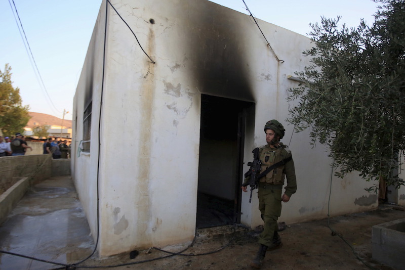 An Israeli soldier walks past a house that had been torched in a suspected attack by Jewish extremists killing an 18-month-old Palestinian child, injuring a four-year-old brother and both their parents at Kafr Duma village near the West Bank city of Nablus July 31, 2015. Photo courtesy of REUTERS/Abed Omar Qusini
*Editors: This photo may only be republished with RNS-JEWISH-EXTREMISTS, originally transmitted on August 24, 2015.