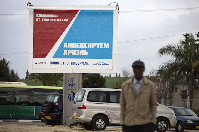 A man walks in front of a Yisrael Beitenu party campaign billboard in the southern city of Ashkelon. This seaside city, once ruled by the Greeks and Phoenicians, is now largely populated by Russians. Picture taken February 8, 2015. Photo courtesy REUTERS/Amir Cohen