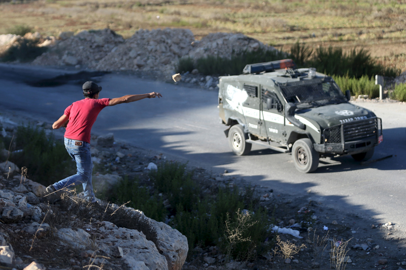 A Palestinian throws a stone at Israeli police vehicle during a protest against Israeli police raid on Jerusalem's al-Aqsa mosque, near Israel's Ofer Prison near the occupied West Bank city of Ramallah on September 17, 2015. Photo courtesy of REUTERS/Mohamad Torokman 
*Editors: This photo may only be republished with RNS-AQSA-TENSION, originally transmitted on Sept. 17, 2015.