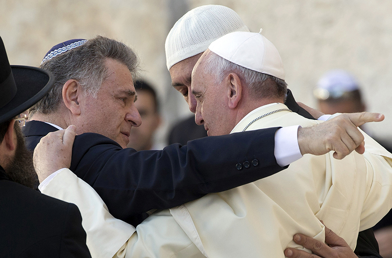 Pope Francis embraces two good friends of his traveling with him, Argentine Rabbi Abraham Skorka, left, and Omar Abboud, leader of Argentina's Muslim community, partially seen behind the pope, as he visits the Western Wall in Jerusalem's Old City, Israel, Monday, May 26, 2014. Both friends joined the pontiff's official delegation for the trip in a sign of interfaith friendship. (AP Photo/Andrew Medichini, Pool)