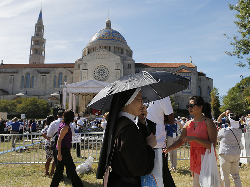 A nun provides shade for herself with an umbrella prior to Pope Francis holding the Canonization Mass for Friar Junipero Serra at the Basilica of the National Shrine of the Immaculate Conception in Washington on September 23, 2015. Photo courtesy of REUTERS/Brian Snyder *Editors: This photo may only be republished with RNS-POPE-SAINT, originally transmitted on Sept. 23, 2015.