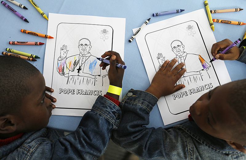 Kaydn Dorsey, 4, left, and Lionel Perkins, 4, draw on a coloring sheet bearing the image of Pope Francis as they wait for him to arrive on a visit to Catholic Charities of the Archdiocese of Washington on September 24, 2015, in Washington. Photo courtesy of REUTERS/David Goldman/Pool