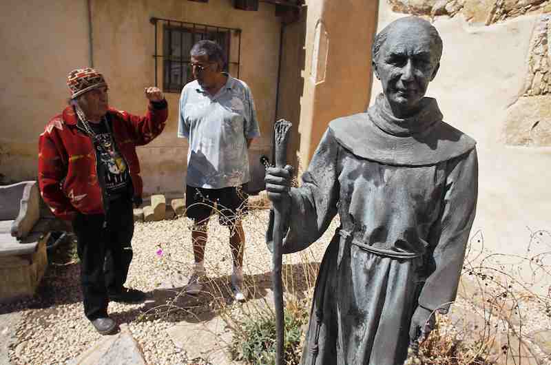 Chief Tony Cerda (L) of the Costanoan Rumsen Carmel Tribe of the Ohlone Nation and Rudy Rosales, Tribal Chairperson of the Ohlone Costanoan Esselen Natio, stand next to a statue of Franciscan Friar Junipero Serra at the Carmel Mission in Carmel, California, in this file photo taken September 15, 2015. Vandals in California on Sunday toppled a statue of Junipero Serraat the Catholic mission in Carmel where he is buried. Photo by Michael Fiala courtesy of Reuters