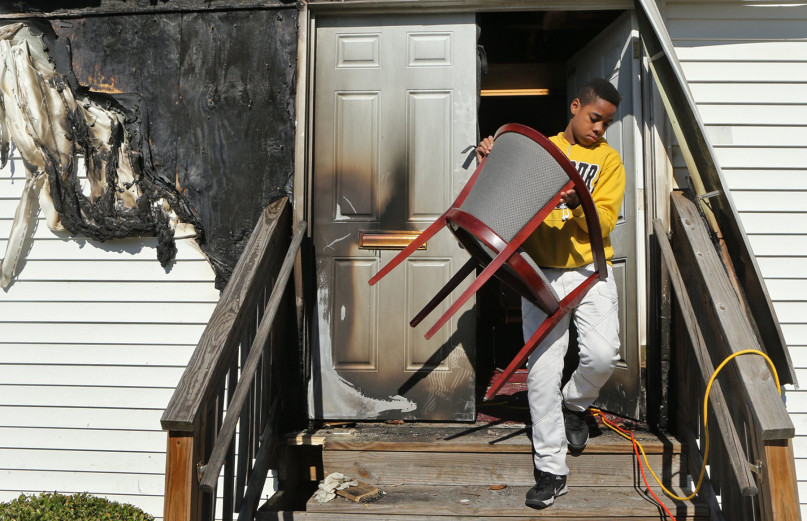 Tony McMiller, 13, helps carry chairs outside on Sunday, Oct. 18, 2015, at the New Life Missionary Baptist Church in St. Louis, so that parishioners could sit in the yard. The church was damaged by an arson fire on Saturday, Oct. 17, 2015, so the service was held outside. Photo by J.B. Forbes, courtesy of St. Louis Post-Dispatch