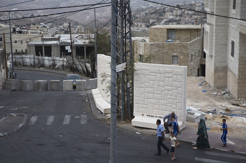 Palestinians walk next to a newly erected temporary concrete wall, that measures around 10 meters, in Jerusalem October 19, 2015. Israel has deployed troops in and around Jerusalem and erected roadblocks in Palestinian neighborhoods in East Jerusalem to try and stop the most serious outbreak of Palestinian street attacks since an uprising in 2000-2005. Photo courtesy REUTERS/Ronen Zvulun