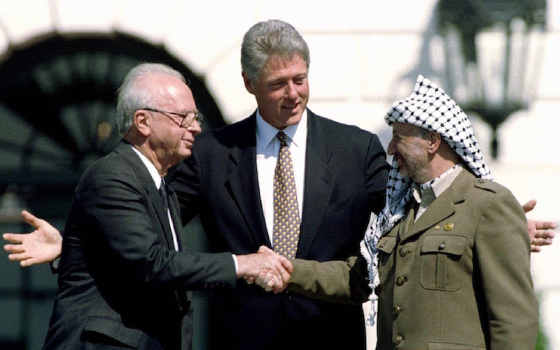 U.S. President Bill Clinton looks on as Israeli Prime Minister Yitzhak Rabin (L) and Palestine Liberation Organization leader Yasser Arafat shake hands after the signing of the Israeli-PLO peace accord at the White House in this September 13, 1993 file photo.   Photo courtesy REUTERS/Gary Hershorn


