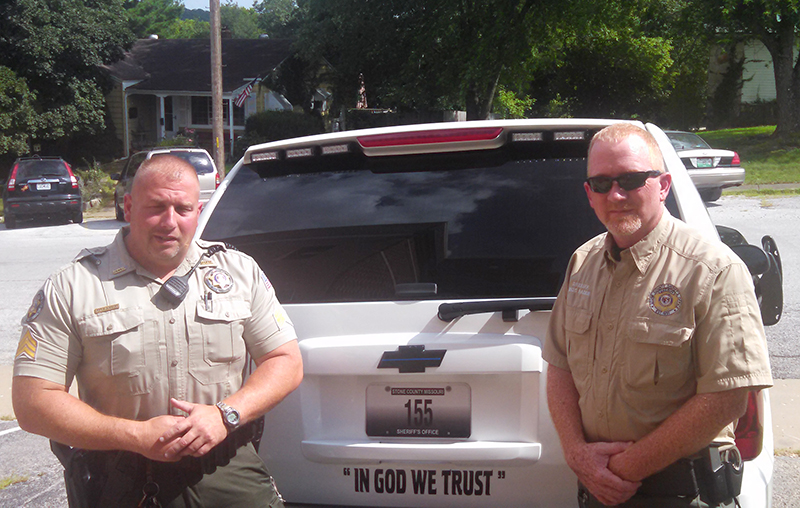Sgt. Cuzzort, left, and Sherriff Rader of the Stone County Sherriff's Office in Missouri, stand in front of a patrol vehicle with a 'In God We Trust' bumper sticker. Photo courtesy of Stone County Sherriff's Office