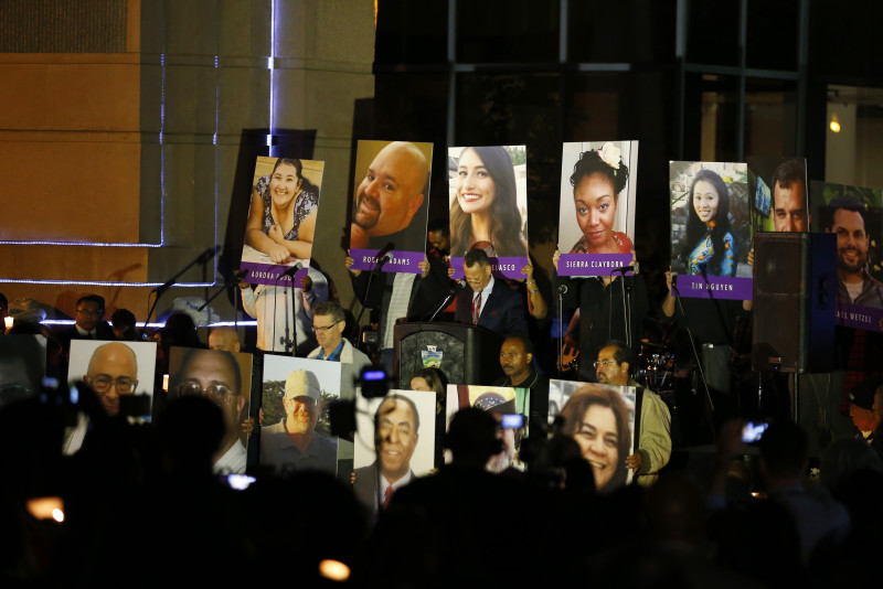 People hold photos of the mass shooting victims during a moment of silence at a vigil in San Bernardino, California December 7, 2015. Photo by Mike Blake, courtesy of REUTERS.