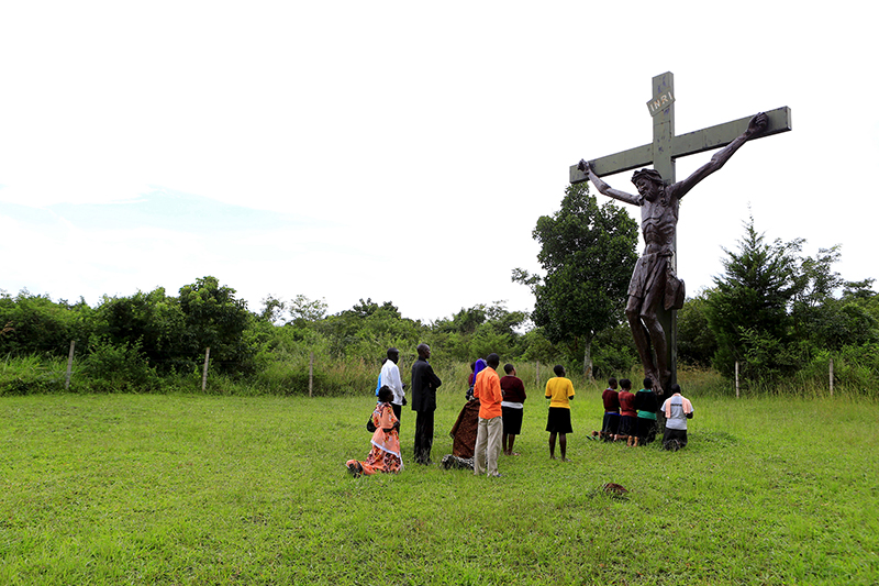 Catholic faithful pray in front of a cross of Jesus Christ erected by a roadside in Kakoge, north of Uganda's capital Kampala, on October 18, 2015. Photo courtesy of REUTERS/James Akena