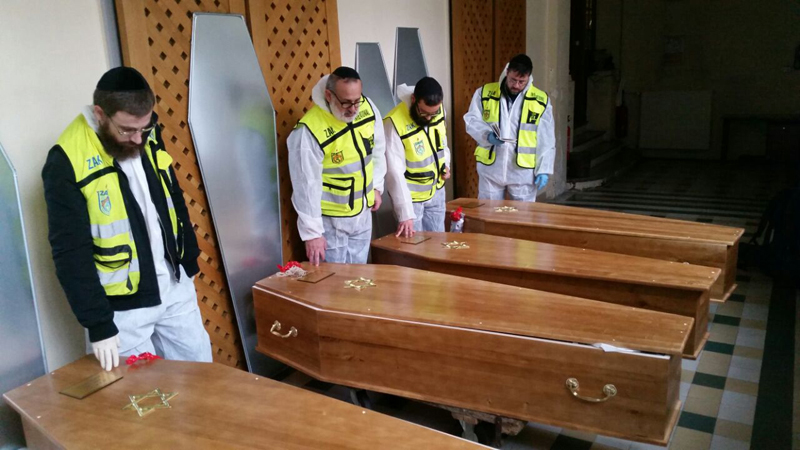 Members of the Zaka emergency response team pray beside the coffins of four victims of an attack at a kosher supermarket, before their transport from Paris to Israel for burial, in Paris, in this picture released by Zaka on January 12, 2015. Photo courtesy of REUTERS/Zaka/Handout via Reuters