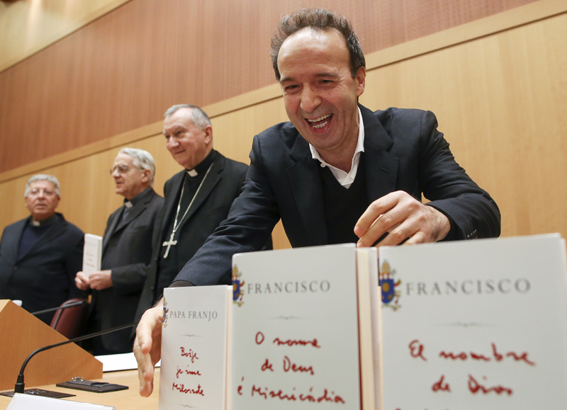 Italian actor Roberto Benigni, far right, takes a copy of Pope Francis' book 