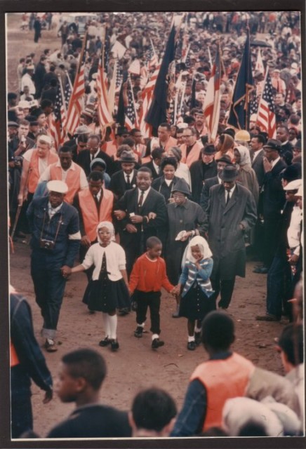 The last day of the Selma March as the Marchers leave St. Jude's and March to the Alabama State Capitol. F.D. Reese is in hat and coat, marching from Selma to Montgomery, behind and to the right of children.