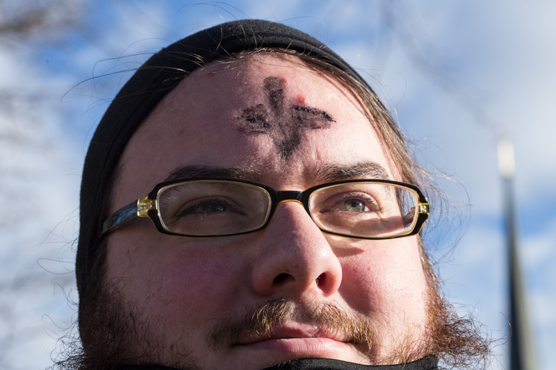 Ministerial intern Shea Zellweger, waves to passing cars along Mission Rd. in Prairie Village, Kan., on Feb. 10, 2016. For the fourth year, Colonial Church, United Church of Christ, is offering drive thru service on Ash Wednesday. Religion News Service photo by Sally Morrow