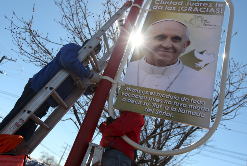 Workers put up a poster with an image of Pope Francis along a street at the border with the U.S. in Ciudad Juarez, Mexico, on February 6, 2016. Photo courtesy of REUTERS/Jose Luis Gonzalez *Editors: This photo may only be republished with RNS-POPE-MEXICO, originally transmitted on Feb. 10, 2016.