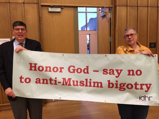 Rabbi Charles Feinberg, left, executive director of the not-for-profit Interfaith Action for Human Rights, and Sandra Miller, an IAHR supporter and member of Seekers Church in Washington, D.C., hold up a banner created by Interfaith Action for Human rights in the hopes that houses of worship will order and prominently display them. Religion News Service photo by Lauren Markoe