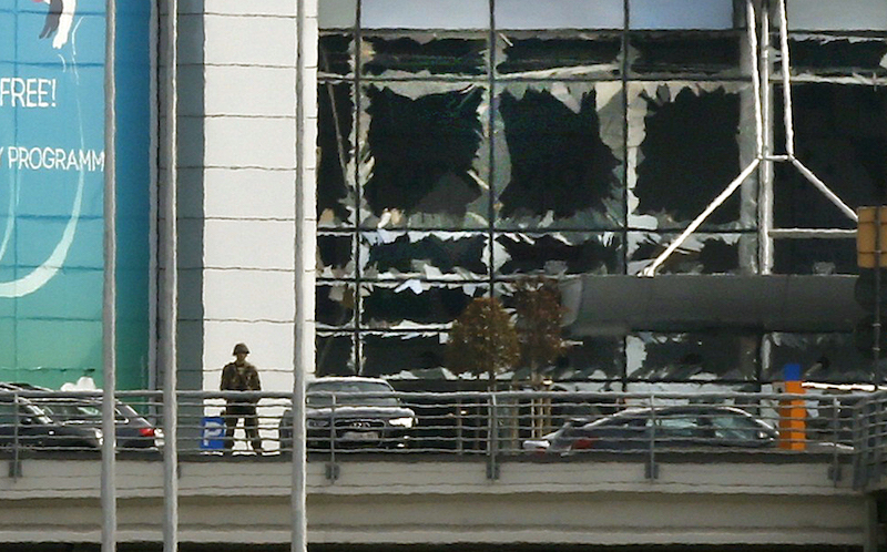 A soldier stands near broken windows after explosions at Zaventem airport near Brussels, Belgium, March 22, 2016.  Photo courtesy  REUTERS/Francois Lenoir 