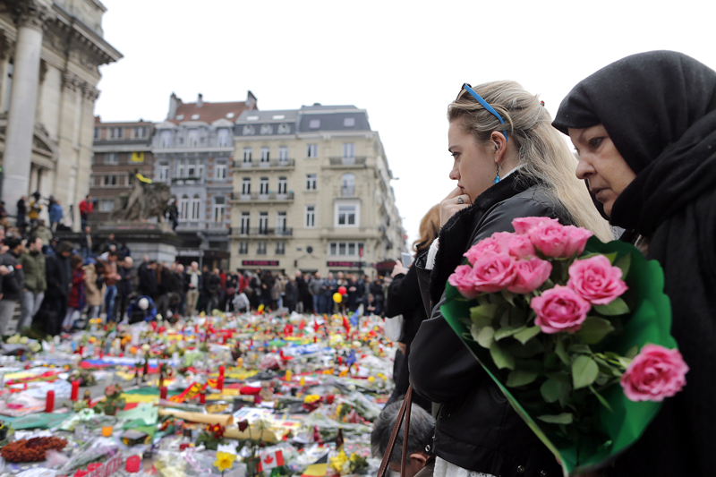People observe a minute of silence at a street memorial to victims of Tuesdays's bombings in Brussels, Belgium, on March 24, 2016. Photo courtesy of REUTERS/Christian Hartmann