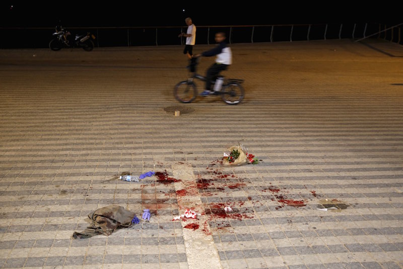 A boy rides past blood stains where, according to Israeli police spokesperson, at least 10 Israelis were stabbed, in the popular Jaffa port area of Tel Aviv, Israel on March 8, 2016. Photo courtesy of REUTERS/Amir Cohen