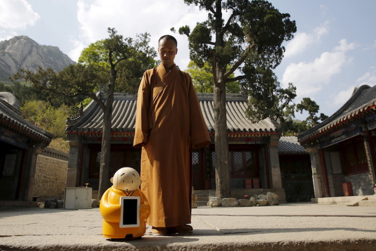 Master Xianfan looks at robot monk Xian'er as he prepares to pose for photograph in the main building of Longquan Buddhist temple on the outskirts of Beijing, April 20, 2016.  Photo courtesy REUTERS/Kim Kyung-Hoon   
