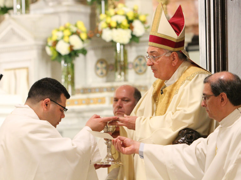 Bishop Nicholas DiMarzio of Brooklyn, N.Y., presents the chalice and paten to the Rev. Jason Espinal during his ordination at the Co-Cathedral of St. Joseph in Brooklyn on June 28, 2014. Photo by Gregory A. Shemitz, courtesy of Catholic News Service
