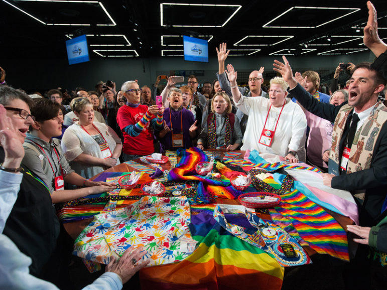 Supporters of LGBTQ rights in the United Methodist Church rally around the central Communion table at the close of the 2016 United Methodist General Conference in Portland, Ore. Photo by Mike DuBose, courtesy of UMNS