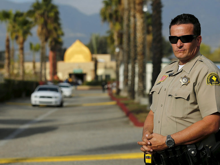 A police officer stands watch as people leave Friday prayers at the Dar Al Uloom Al Islamiyah-Amer mosque where shooting suspect Syed Rizwan Farook was seen two to three times a week at lunch time, in San Bernardino, California on December 4, 2015. Authorities are investigating the San Bernardino, California, shooting as an 