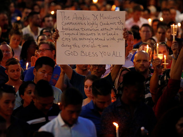 A man holds up a sign saying Arab Muslims condemn the attack as he takes part in a candlelight memorial service on June 13, 2016, the day after the mass shooting at the Pulse gay nightclub in Orlando, Fla. Photo courtesy of REUTERS/Carlo Allegri
