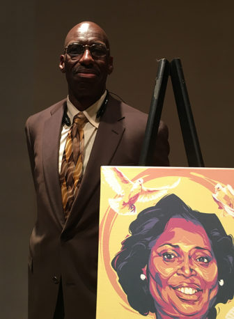 Melvin Graham, alongside a portrait of his sister, Cynthia Graham Hurd, a librarian killed in the massacre at Emanuel AME church on June 17, 2015. Graham and his brothers have established a foundation that honors their slain sister by providing books to disadvantaged young people. RNS photo by Lauren Markoe