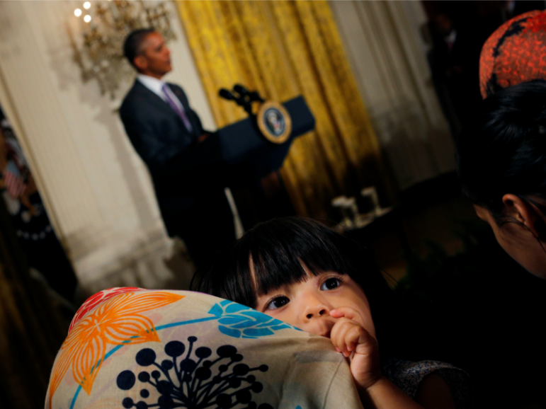 Sophia Ahmadinejad, a 2-year-old refugee from Afghanistan, listens as President Obama delivers remarks at an Eid al-Fitr reception at the White House on July 21, 2016. Photo by Carlos Barria/REUTERS