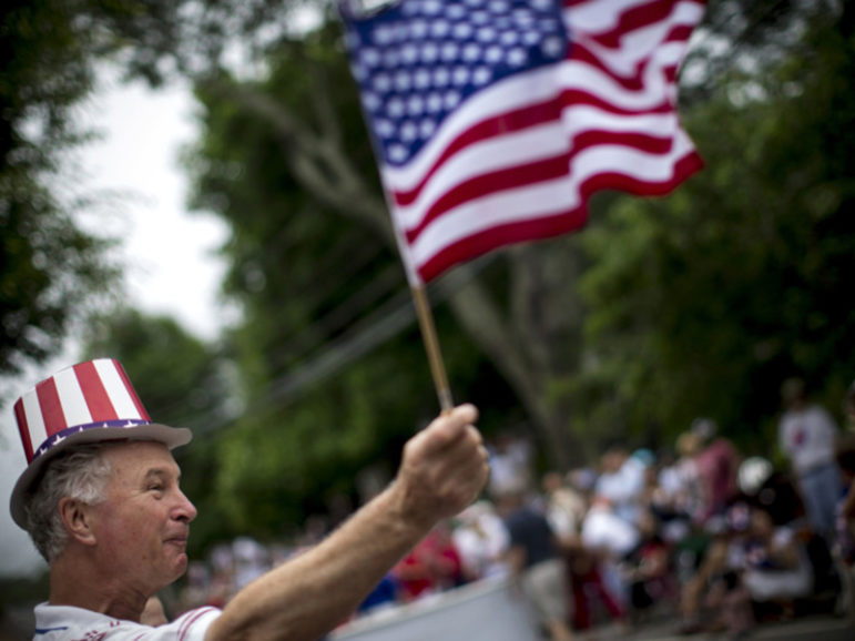 A man waves an American flag as he watches a July Fourth parade in the village of Barnstable, Massachusetts, on July 4, 2014. Photo courtesy of Reuters/Mike Segar
