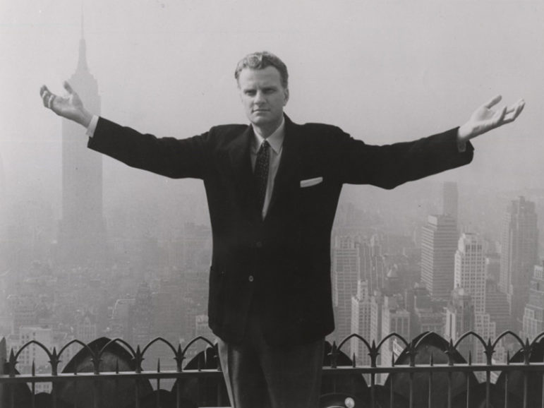 Evangelist Billy Graham stands on the roof-top of a skyscraper in New York City with the midtown skyline behind him to symbolize his New York crusade. Religion News Service file photo courtesy of Archives of the Billy Graham Center, Wheaton, Illinois.