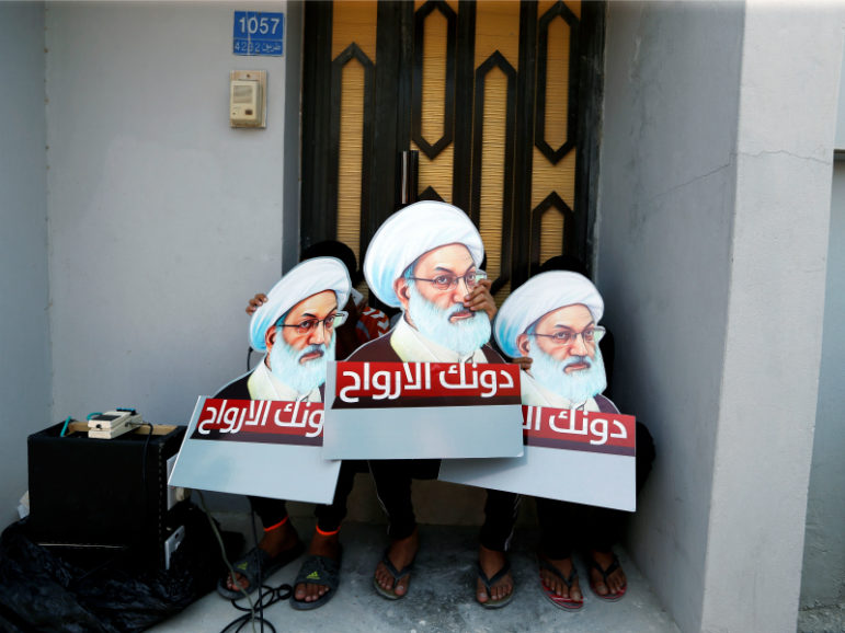 Protesters holding placards with images of Bahrain's leading Shiite cleric, Isa Qassim, shout religious slogans during an anti-government protest after Friday prayers Aug. 12, 2016, in the village of Diraz, west of Manama, Bahrain. The placards read, 