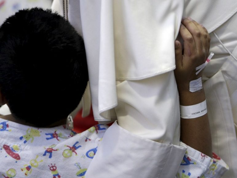 A young patient touches Pope Francis during his visit Feb. 14, 2016, to pediatric hospital 
